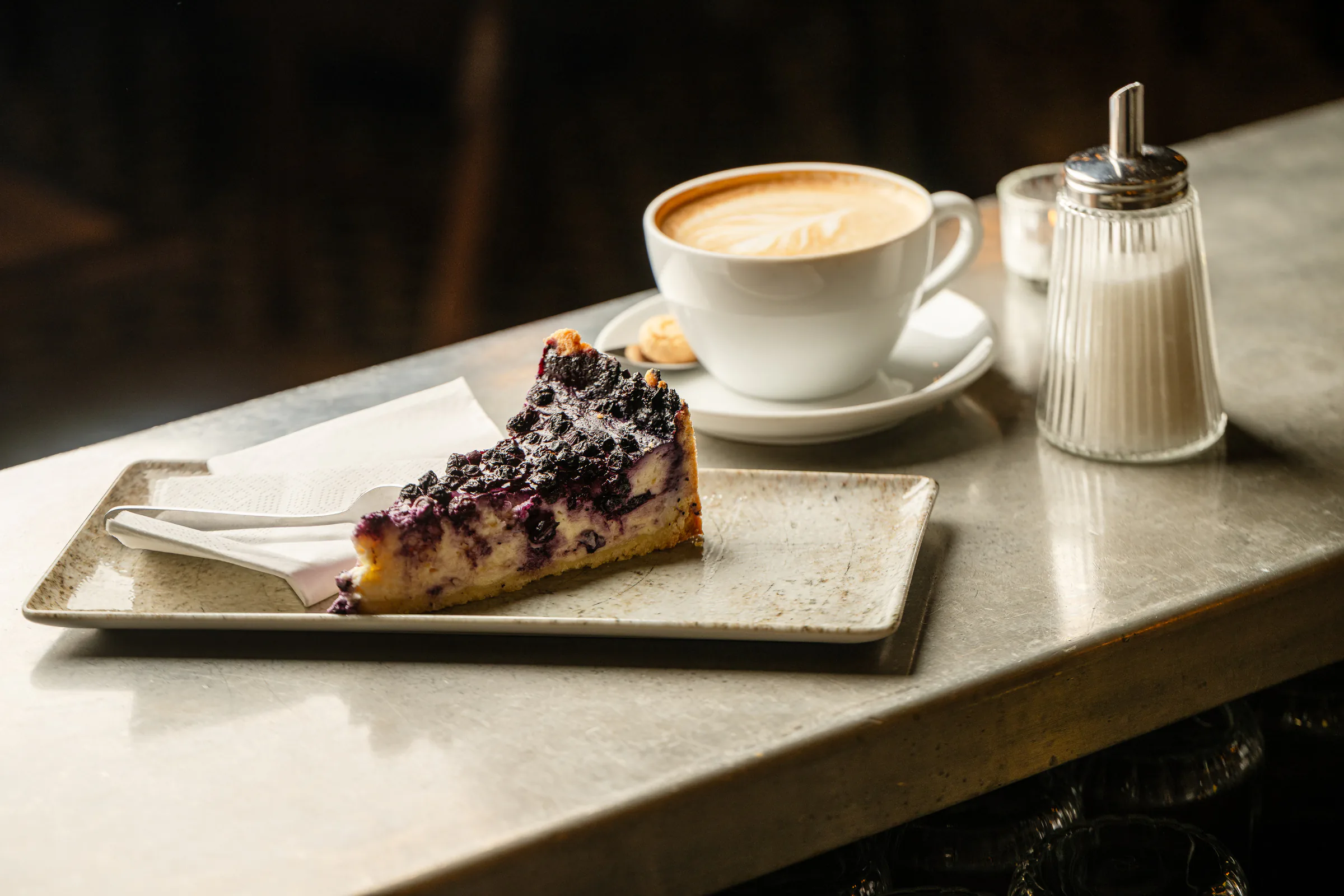 Blaubeerkuchen und Cappuccino auf dem Tresen