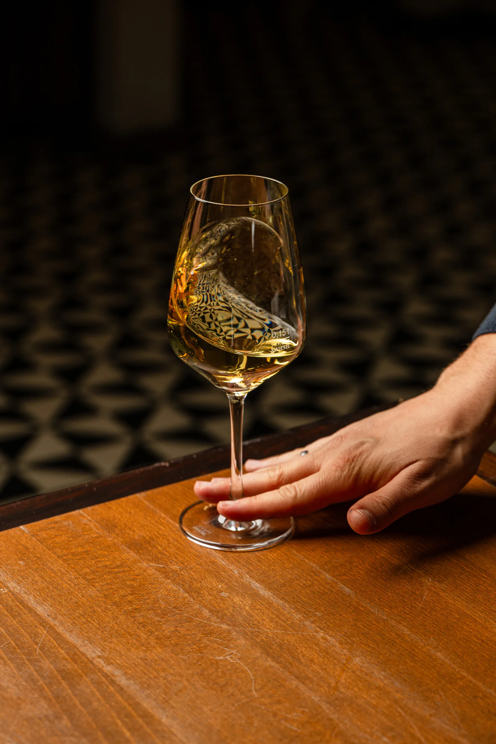 Ein Glas Weißwein wird auf den Tisch gestellt