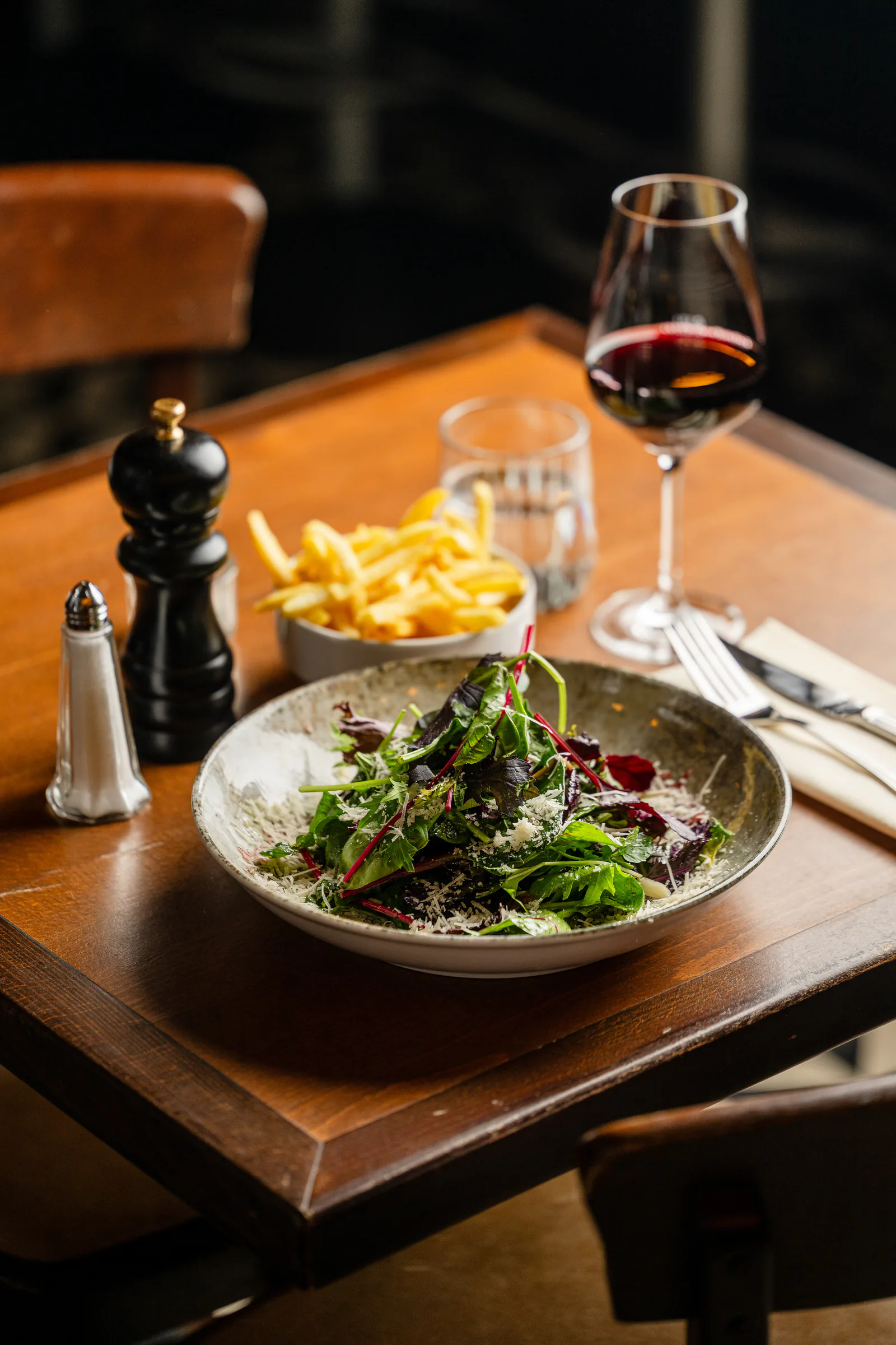 Gedeckter Tisch mit Salat, Pommes frites und Rotwein